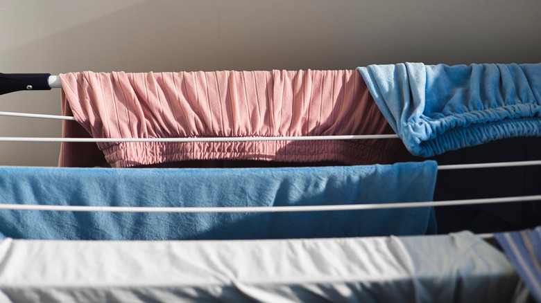 Pink and blue clothes hanging folded over a white drying rack