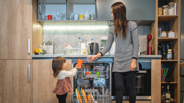 mom and child fill dishwasher