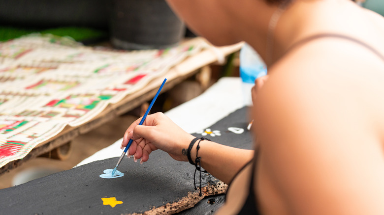 woman painting stars on wood block