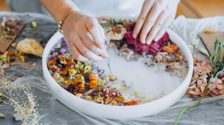 A woman arranges dried flowers in a silicon mold.