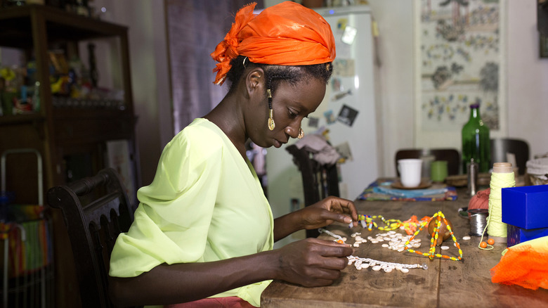 A woman works on a craft project while sitting at the kitchen counter.
