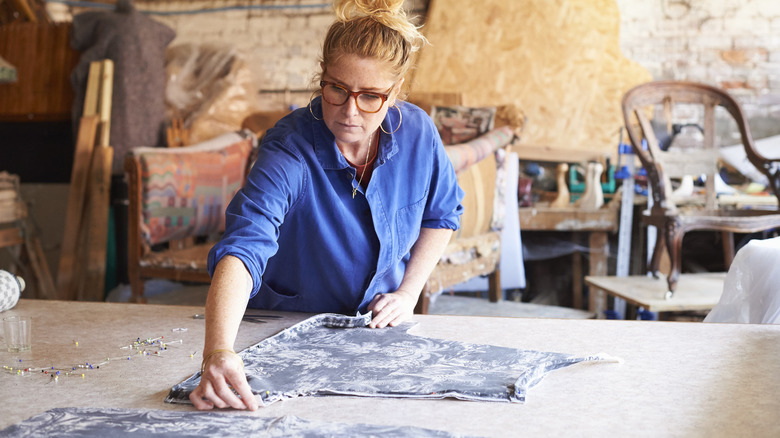 An upholsterer pinning fabric on her cutting table