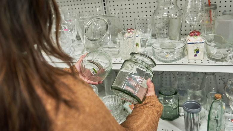 Woman looking at glass jars at thrift store