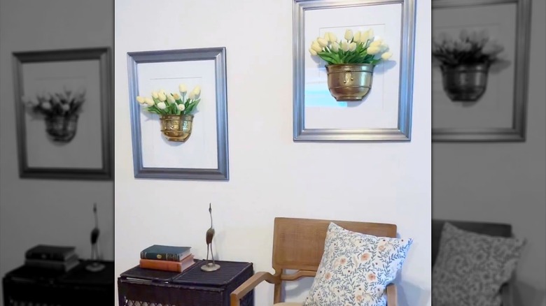 Framed pocket or half vases filled with faux flowers are mounted to the wall in an entryway.
