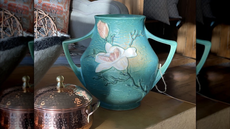 A vintage blue and white floral Roseville vase on a table.
