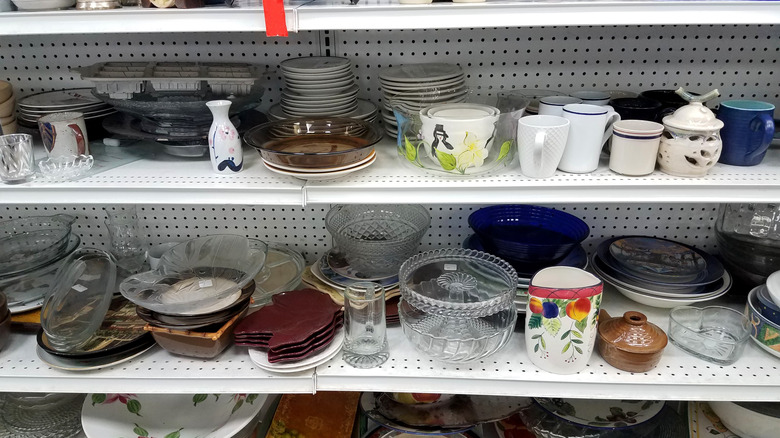Shelves at a thrift store with pottery and ceramics on it.
