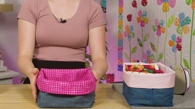 A woman shows off two lined denim storage containers she sewed.