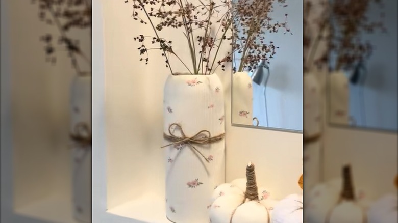 A vase covered in a patterned shirt sleeve