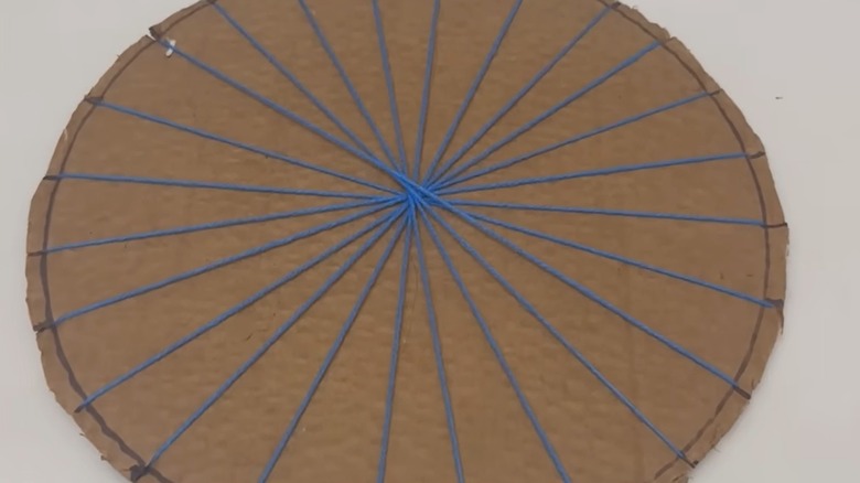Yarn bisects a cardboard circle into a starburst shape.