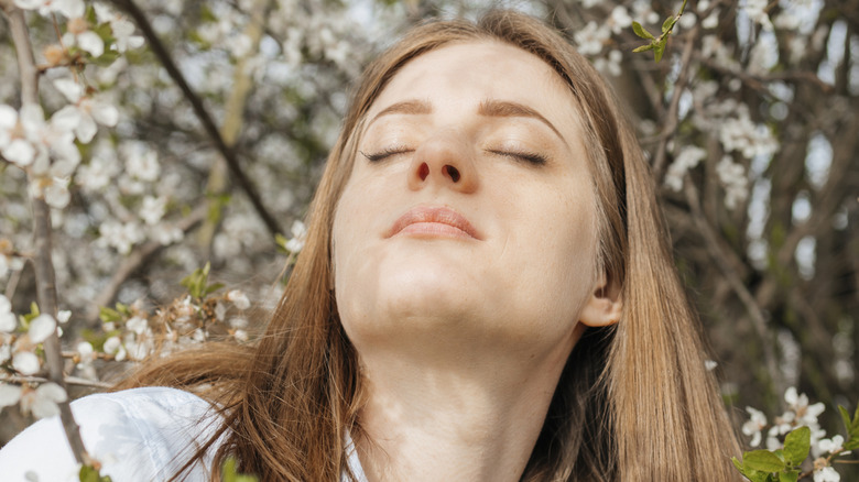 Woman relaxing smelling white flowering trees in garden