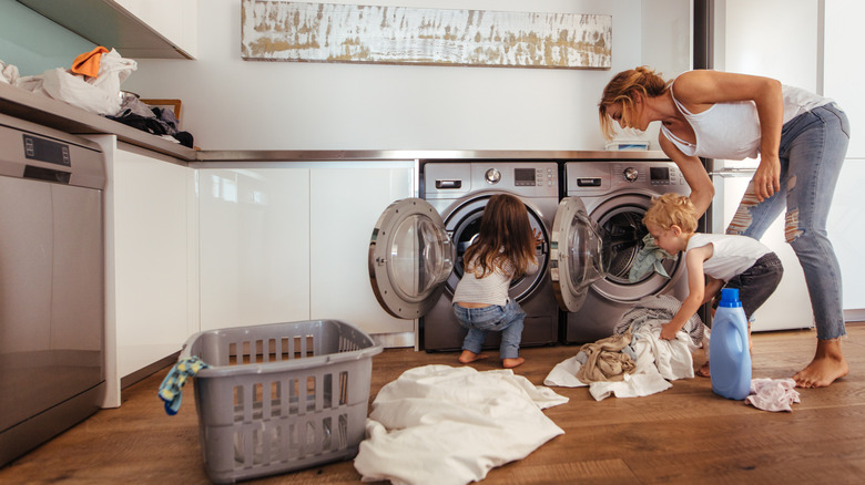 Mom with two young daughters doing laundry.