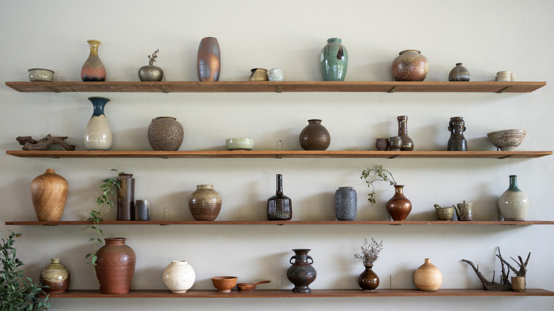 A collection of vintage ceramic pieces are displayed on open wooden shelves