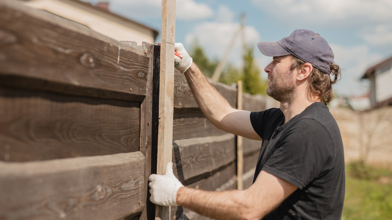 A brown worn wooden fence with horizontal lumber pieces.