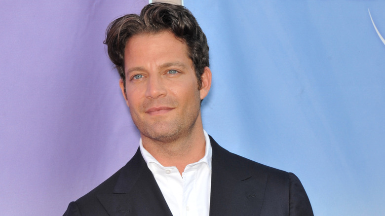 Nate Berkus posing in front of blue and purple red carpet backdrop
