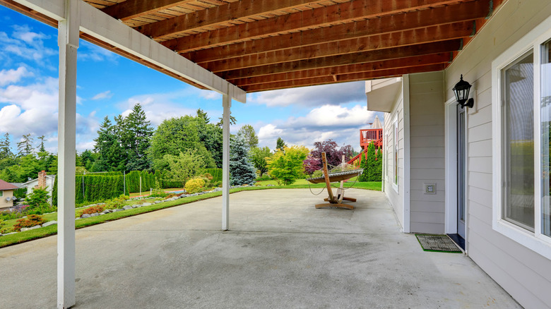 A covered gray concrete patio area outside a home