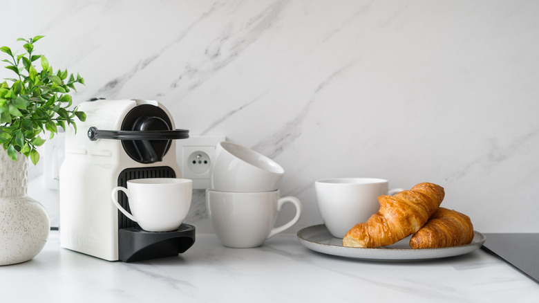Stack of coffee mugs and coffee machine on work surface