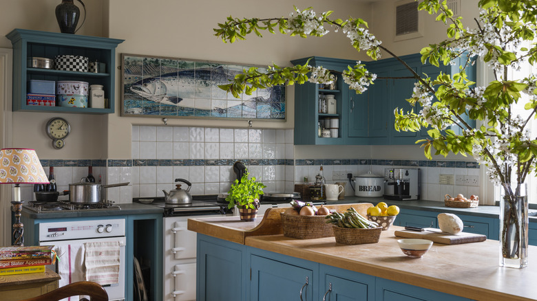 Blue kitchen with fish tiled decor fresh vegetables and books