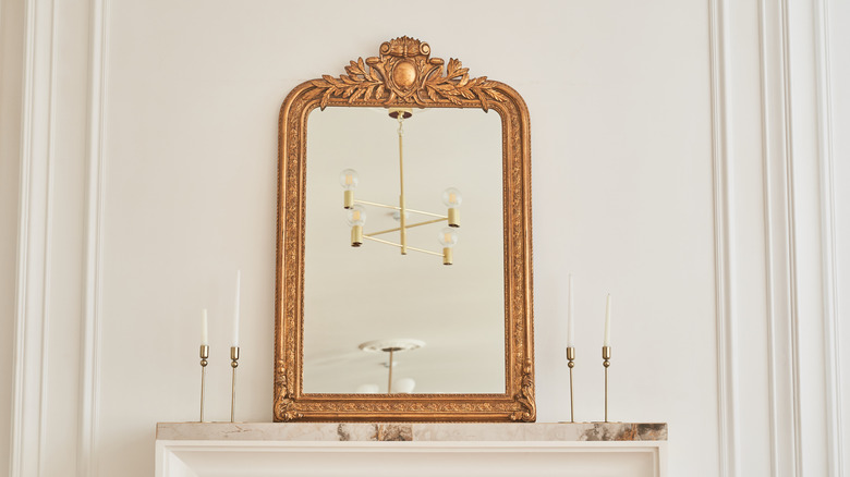 A vintage mirror with an ornate gold frame above a mantle