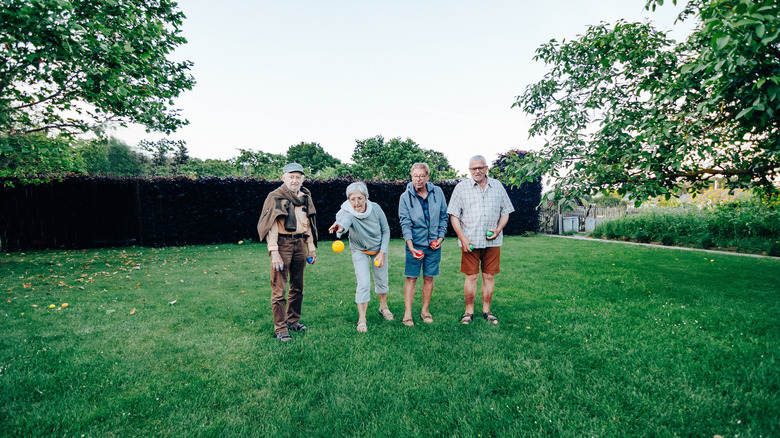 Seniors playing bocce ball in a backyard
