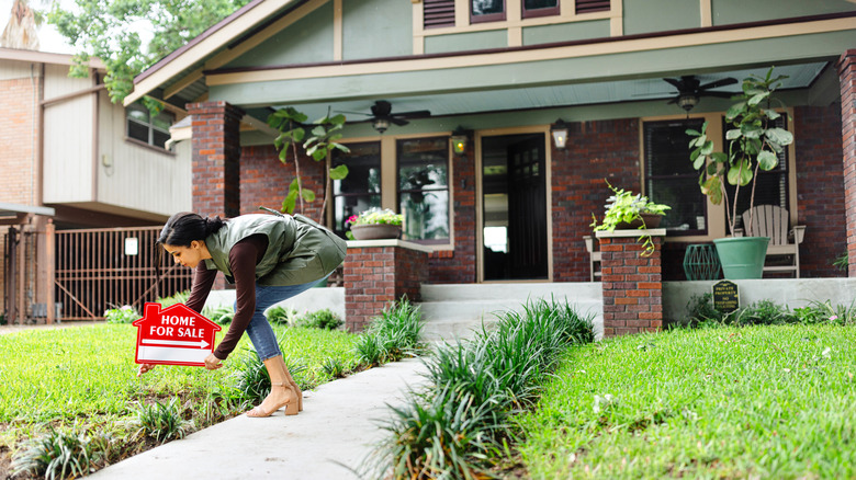 An agent putting a 'for sale' sign in front yard