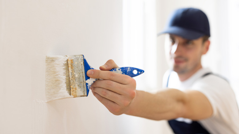 Man brush painting a wall with a brush