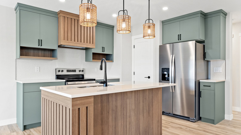 Wood kitchen island in front of kitchen counters, appliances, and gray cabinets.