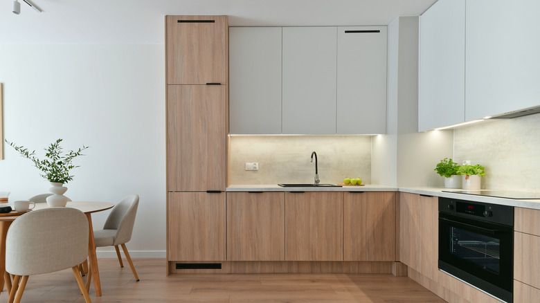 Minimalist kitchen with light wood cabinets, table and chairs.