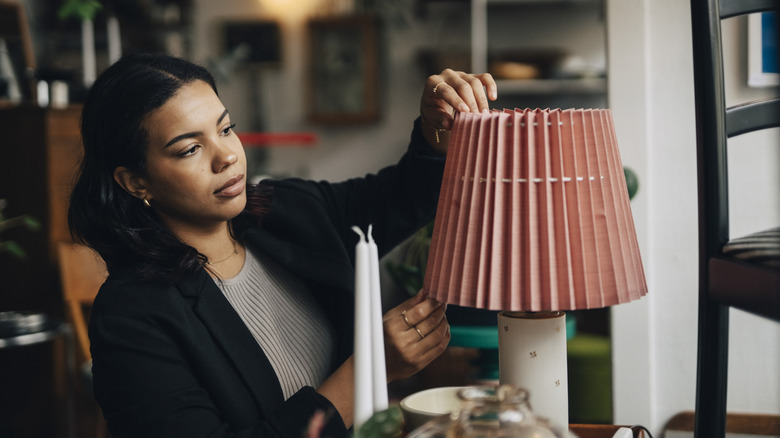Woman adjusting the shade on a lamp