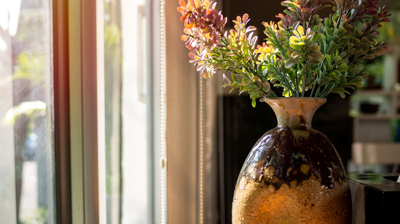 An oversized ceramic vase with flowers on a tabletop