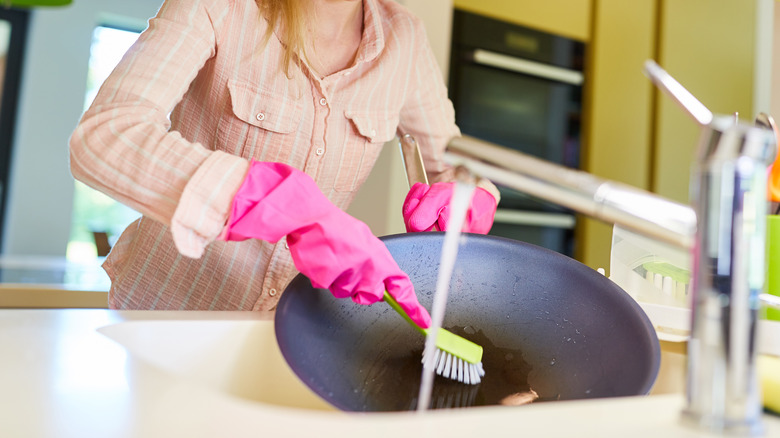 Woman cleans wok in sink