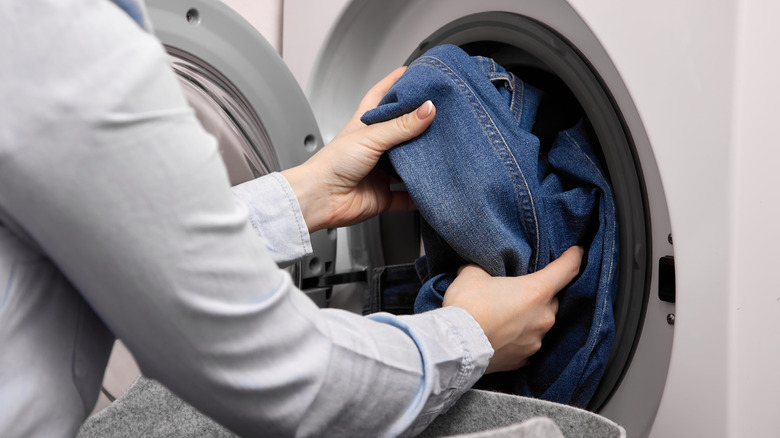 person putting pants in dryer