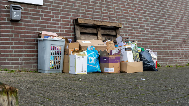 Stack of cardboard boxes and packaging materials placed outside a home for disposal