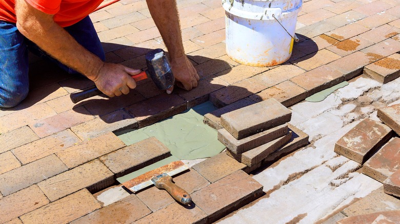 A person working on repairing brick pavers at a residence