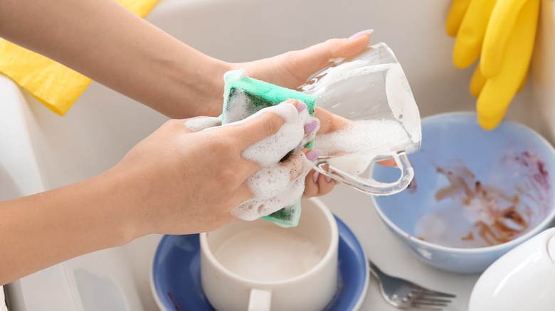 hands washing glass in sink
