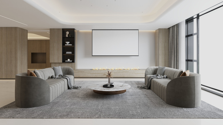 Modern living room with two gray sofas facing each other and large hanging TV screen
