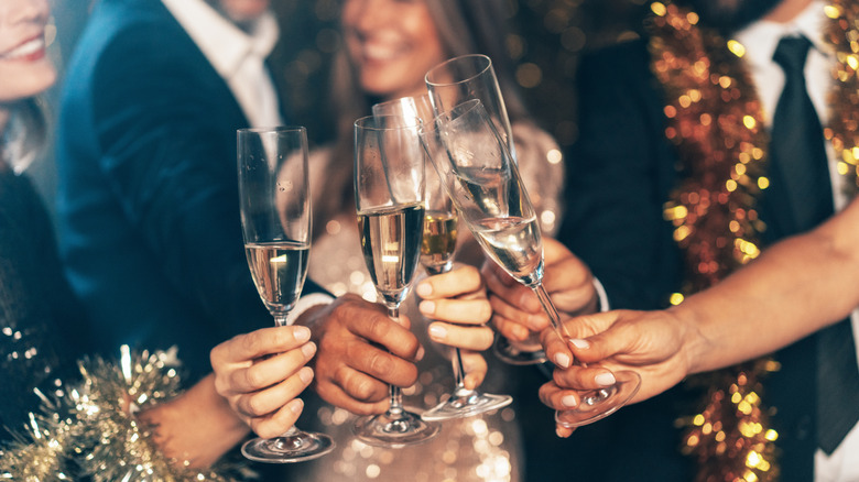 People clinking glasses wearing gold and silver tinsle