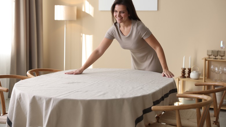 Person adding tablecloth to table