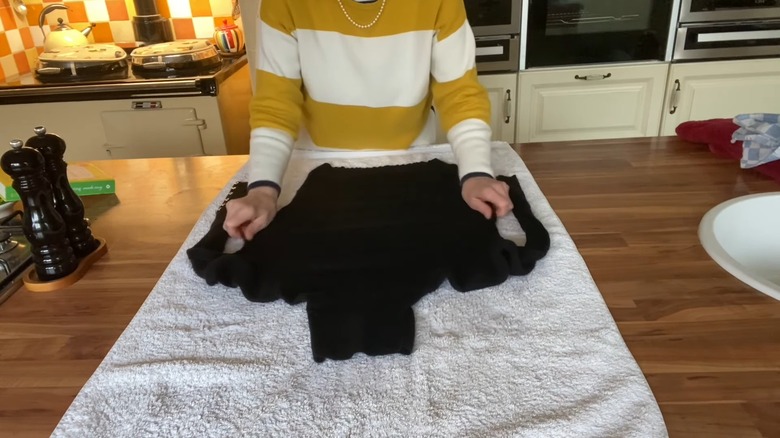 Woman's hands stretching the sides of a black sweater