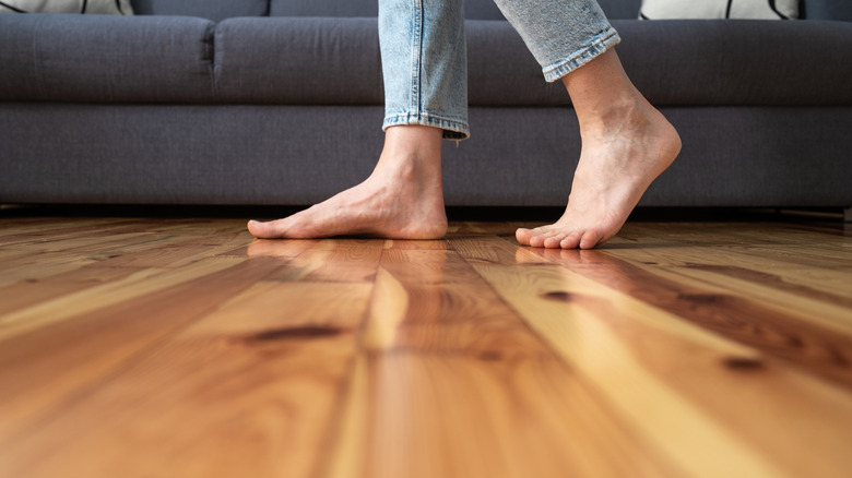 legs walk barefoot on wooden floor near couch in living room