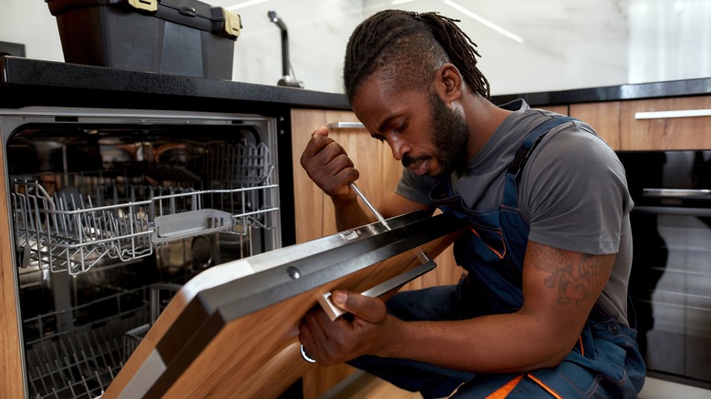 repair man fixing dishwasher