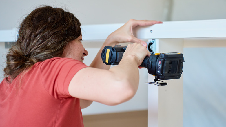 Woman assembling a furniture frame with a cordless drill