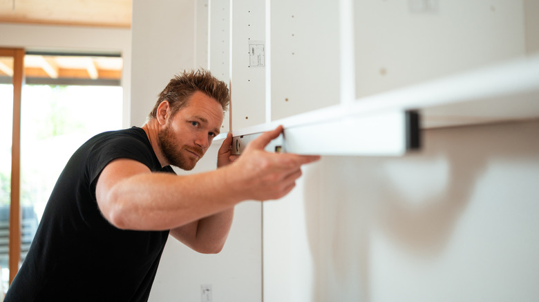 Man using a level on the bottom of a cabinet