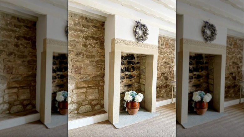 A room with jute wall-to-wall carpet and a natural stone wall and fireplace