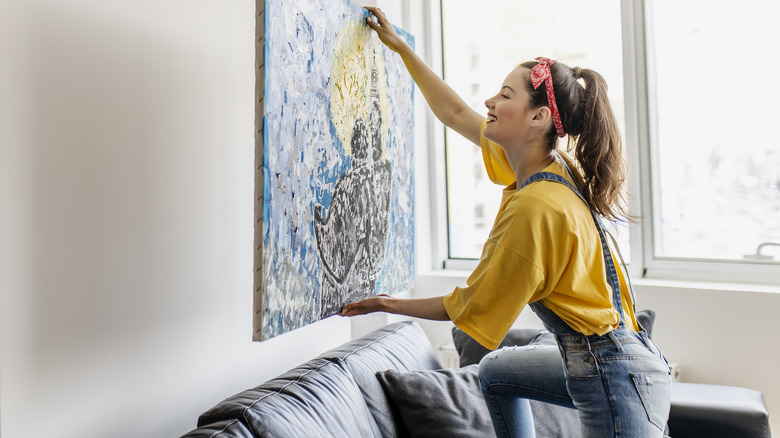 woman putting painting on wall