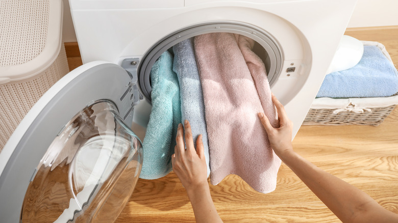 Person loads pastel towels into their washing machine