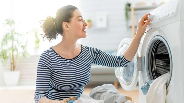 Woman adjusts her washing machine to the 'towel' setting to help freshen up her stinky towels.
