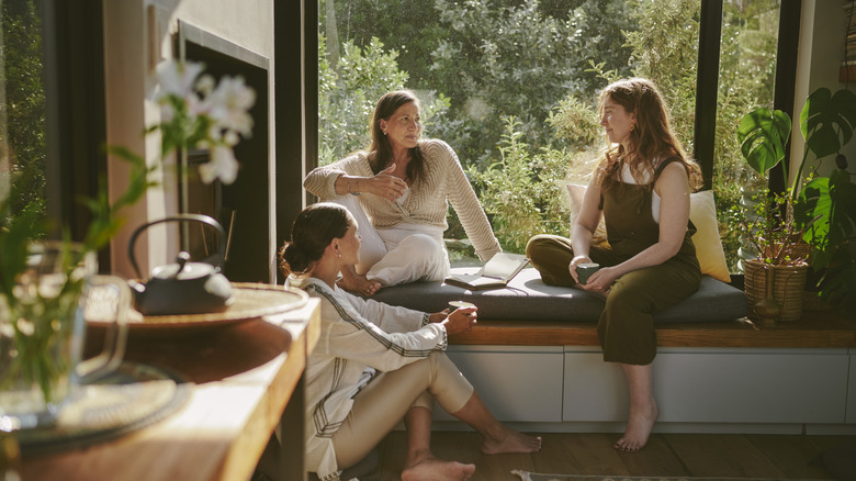 Group of women gathering in a room with a bay window and earthy decor