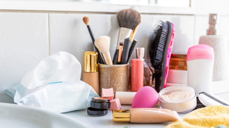 makeup and other toiletries on a messy bathroom counter