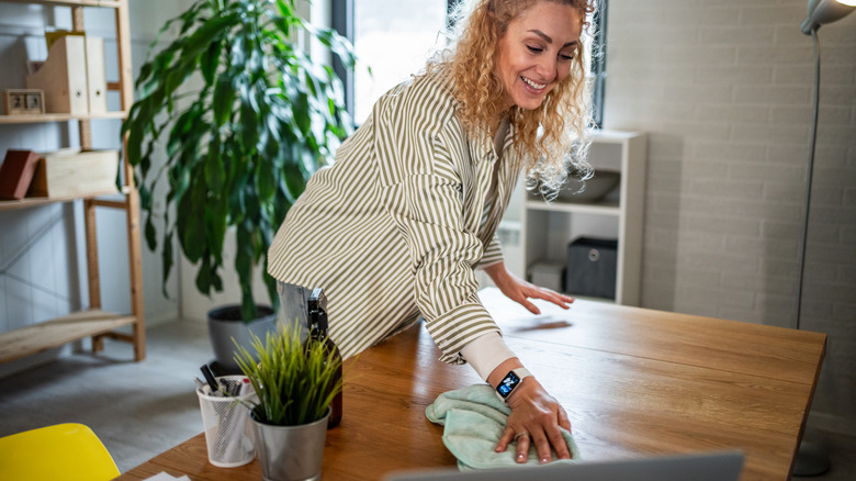 Woman wiping table surface in modern home office
