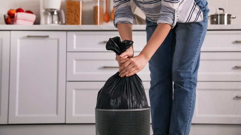 person removing trash bag 